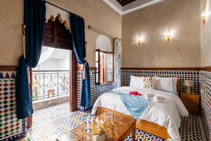 La grande chambre familiale, lit double, rideaux bleus et fenêtre ouverte