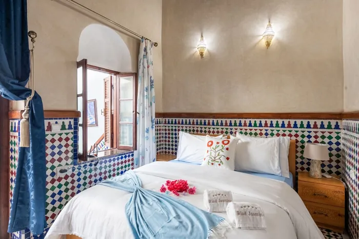 Une chambre du riad, rideaux bleus et fleurs rouges sur le lit