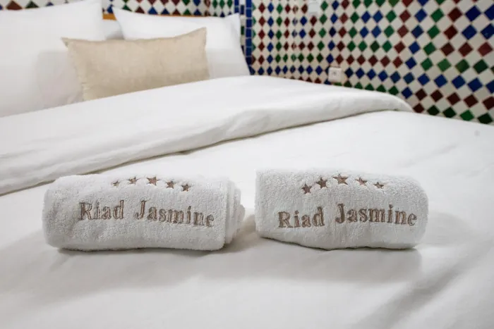 Serviettes brodées Riad Jasmine sur un lit